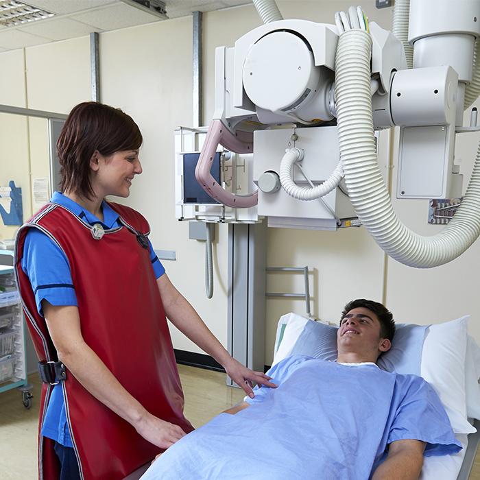 Medical worker wearing lead vest and radiation badge with patient