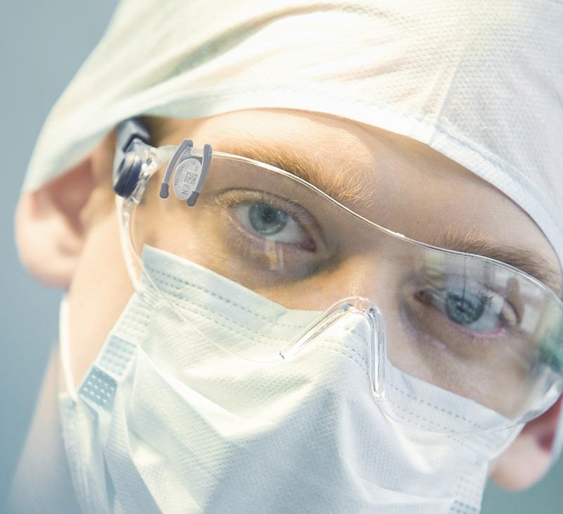 doctor with mask and glasses wearing landauer vision lens of eye dosimeter for radiation safety and measurement